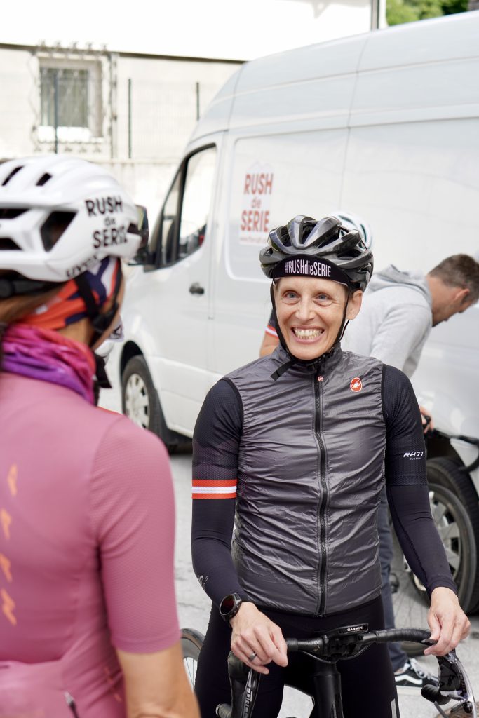 Rennradfahrerin in Frauen-Gruppe fährt durch grüne Alpenlandschaft im Oberpinzgau