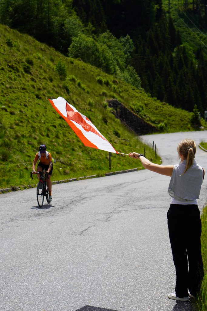 Gruppe rennradfahrender Frauen auf Alpenstraße vor Bergkulisse, gemeinschaftliches Cycling-Event