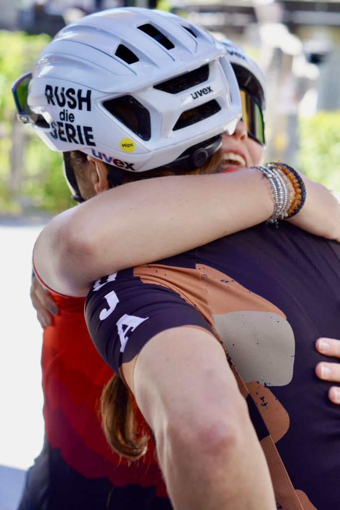 Rennradfahrerinnen in bunter Sportkleidung fahren gemeinsam durch grüne Alpenlandschaft im Oberpinzgau