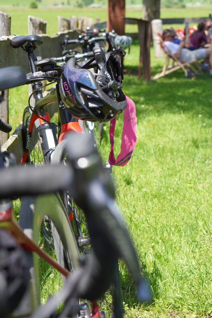 Gruppe rennradfahrender Frauen auf Alpenstraße vor Bergkulisse, gemeinschaftliches Cycling Event